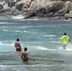 Guardavidas ingresando al mar en Playa La Audiencia con personas alrededor y un muro de rocas al costado