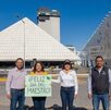 Maestros frente al Centro Expositor deseando con un cartel de feliz día del maestro