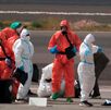 Pasajeros son rociados con desinfectante por personal del gobierno español antes de subir a un barco.