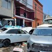 Automóviles impactados por un tráiler y un camión con personas y viviendas alrededor
