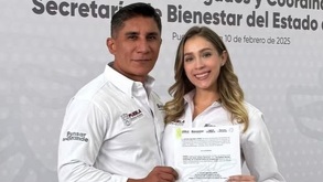 Un hombre y una mujer sonriendo para una fotografía mientras sostienen un documento.