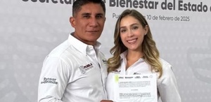Un hombre y una mujer sonriendo para una fotografía mientras sostienen un documento.