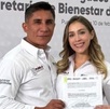 Un hombre y una mujer sonriendo para una fotografía mientras sostienen un documento.