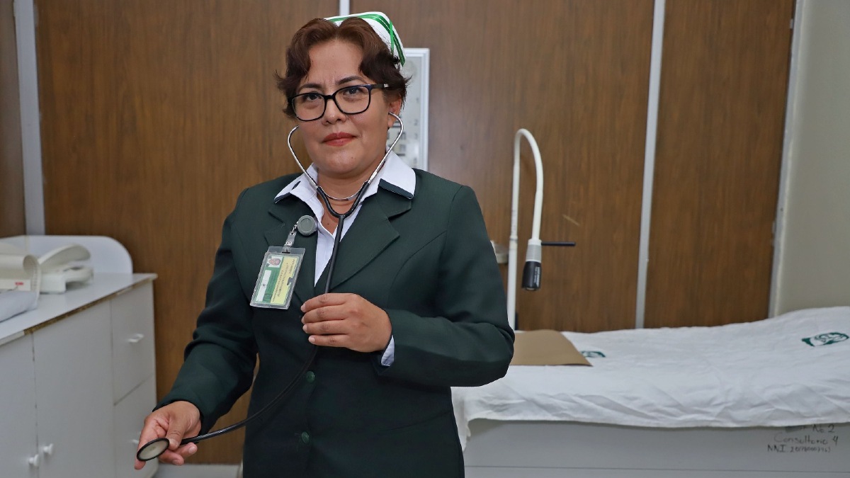 Una enfermera con uniforme verde del imss sostiene un estetoscopio