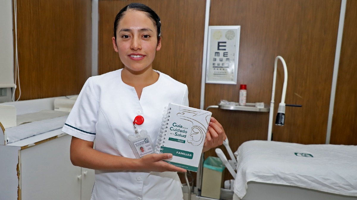 una enfermera del imss con uniforme blanco sostiene una libreta