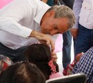 Pepe Chedraui le pone una prótesis auditiva a una niña durante el evento en Puebla