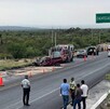 Se observan a varias personas y una camioneta destrozada del frente, en la carretera.