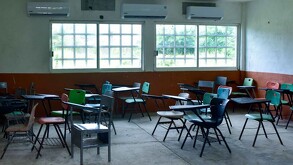 Se observan unas butacas dentro de un salón de clases.