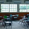 Se observan unas butacas dentro de un salón de clases.