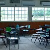 Se observan unas butacas dentro de un salón de clases.