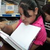 Niña revisa una libreta en una tienda de artículos escolares