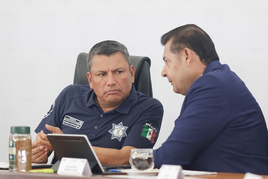Dos hombres con semblante serio hablando en una mesa.