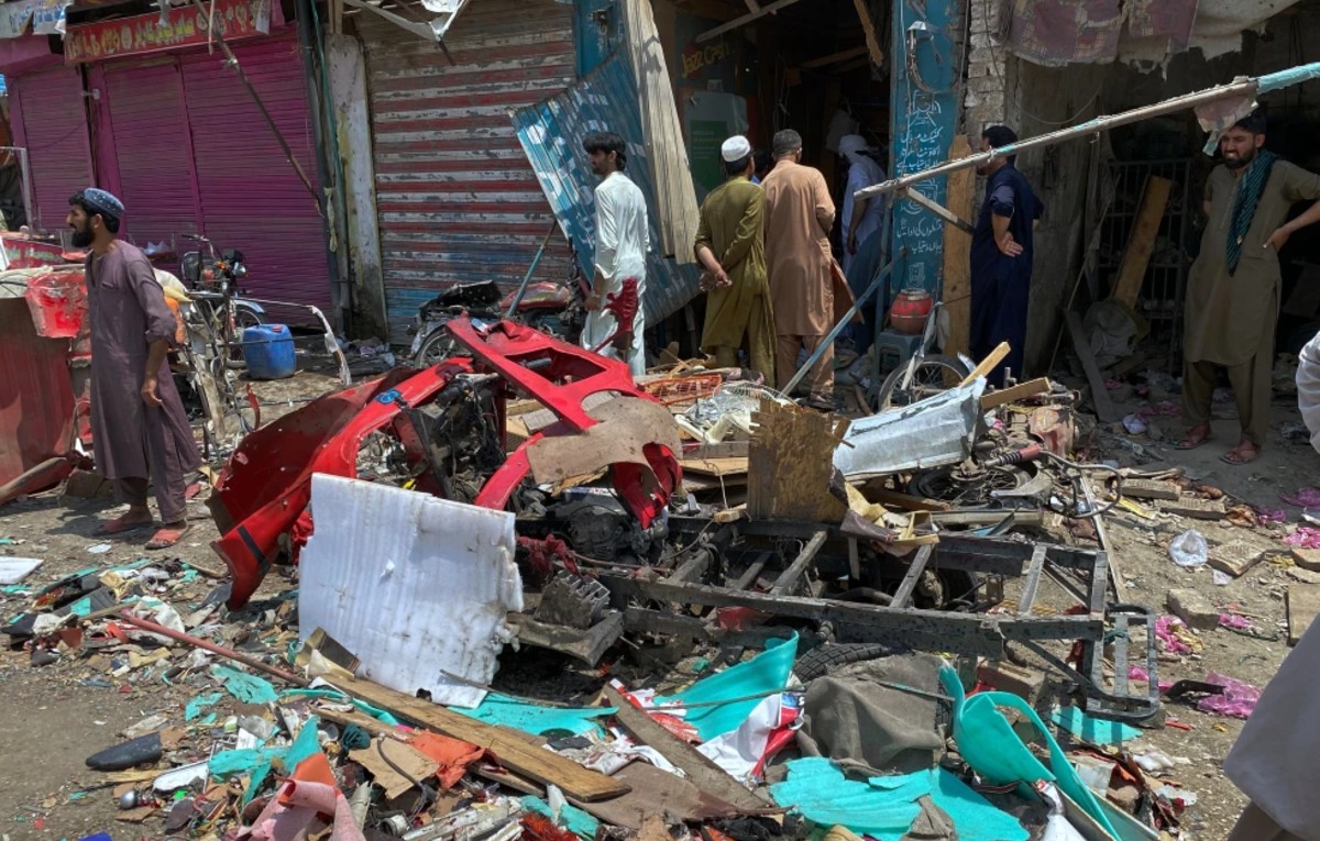 Vecinos de la zona examinan los daños en el lugar donde explotó una bomba en un mercado en Sarai Norag, en Lakki Marwat, un distrito de la provincia paquistaní.