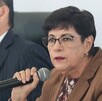 Mujer de lentes y edad avanzada hablando con un micrófono en la mano.