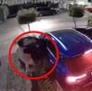 Hombre apuntando a una mujer dentro de un camioneta azul con la puerta del conductor abierta al exterior de una casa en Zapopan