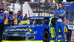 Rubén García Jr. con los brazos cruzados frente a su automóvil 88 en una competencia NASCAR