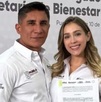 Un hombre y una mujer sonriendo para una fotografía mientras sostienen un documento.
