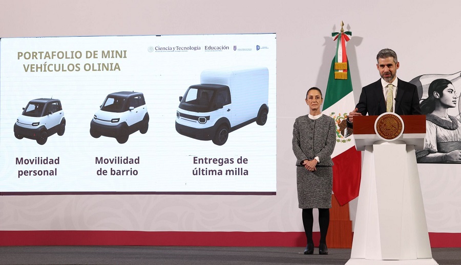 Mujer y hombres parados frente a una presentación de vehículos eléctricos.