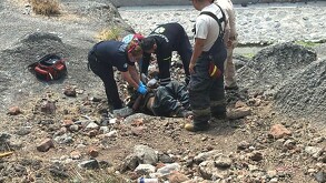 Rescatistas de Protección Civil y Bomberos de Tlaquepaque auxiliando a un hombre recostado sobre arena y escombros al lado de las vías del tren