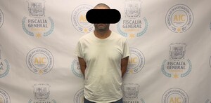Se observa a un hombre con ojos tapados, está detenido y parado.
