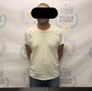 Se observa a un hombre con ojos tapados, está detenido y parado.