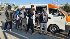 personas esperan el transporte público en una calle en puebla