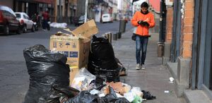 Hombre caminando junto a una montonera de basura en Puebla.
