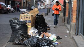 Hombre caminando junto a una montonera de basura en Puebla.