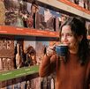 Mujer toma café con el fondo del calendario de las civilizaciones del museo Amparo en Puebla