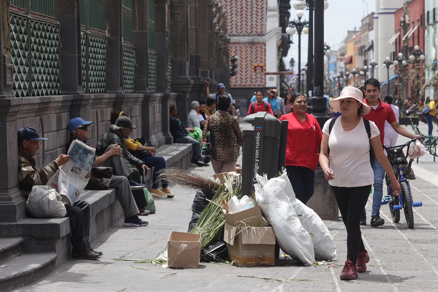 Mujer caminando junto a montones de basura afuera de la Catedral de Puebla.