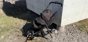 Se observa una carriola negra destruida en una zona de piedras.