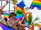 Hombres sin playera ondeando banderas de la comunidad LGBT arriba de un camión durante el Vallarta Pride en Puerto Vallarta