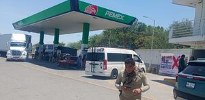 Gasolinera PEMEX con una lona de advertencia a un costado