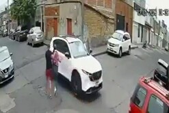 Captura de un video de seguridad que muestra a una mujer siendo llevada a una camioneta por un hombre que le apunta con un arma