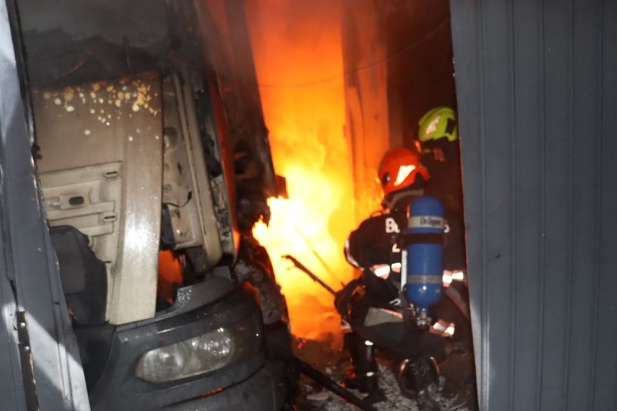 Bomberos de Zapopan sosteniendo una manguera para controlar un incendio dentro de una fábrica de dulces con un camión a un lado
