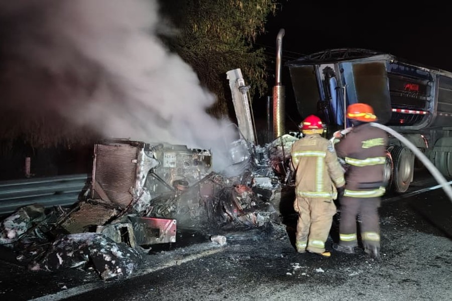 Dos bomberos apagando el incendio de un tráiler emanando humo en medio de la carretera Guadalajara-Colima