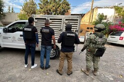 Oficiales de la Fiscalía de Jalisco, policías de investigación y militar del Ejército mexicano parados de espaldas delante de una camioneta de Tlaquepaque