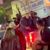 Policías de El Salto a bordo de la caja de una camioneta blanca disparando al aire con personas alrededor