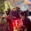 Policías de El Salto a bordo de la caja de una camioneta blanca disparando al aire con personas alrededor