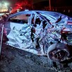 Vista lateral de un automóvil gris destruido y con los fierros retorcidos tras ser impactado por un tráiler