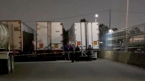 Policías de Zapopan acordonando un área donde con al menos cuatro tráileres estacionados al lado de una malla metálica