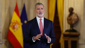 Rey de España Felipe VI hablando delante de la bandera de España y la bandera de las Naciones unidas desenfocadas en el fondo