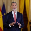 Rey de España Felipe VI hablando delante de la bandera de España y la bandera de las Naciones unidas desenfocadas en el fondo
