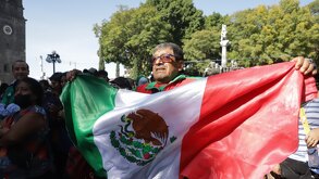 Hombre ondeando la bandera de México en el zócalo de la ciudad de Puebla.