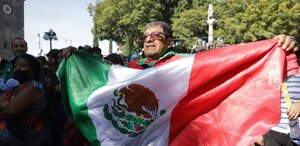 Hombre ondeando la bandera de México en el zócalo de la ciudad de Puebla.