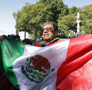 Hombre ondeando la bandera de México en el zócalo de la ciudad de Puebla.