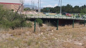 Se observa un puente y hay varios automóviles circulando en la vialidad.