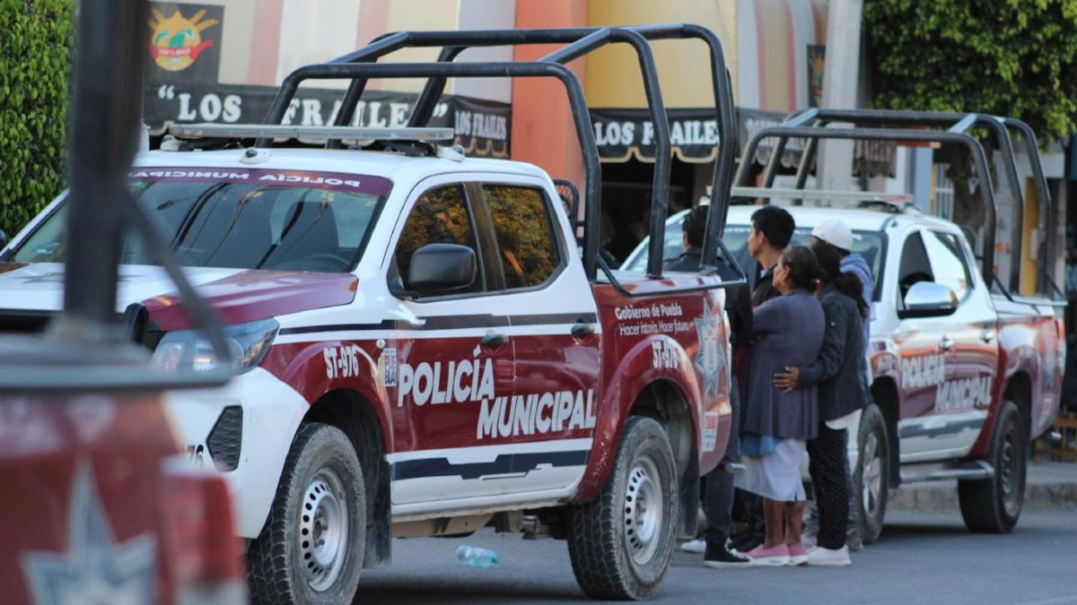 Personas mayores de edad observan un crimen junto a una patrulla de la policía municipal de Tehuacán.