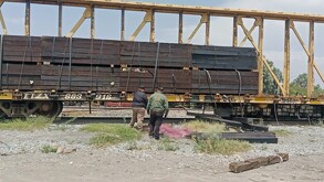 Se observan unas vías del tren, hay unas personas paradas.