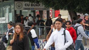 Jóvenes caminando junto a una estación de metrobús.